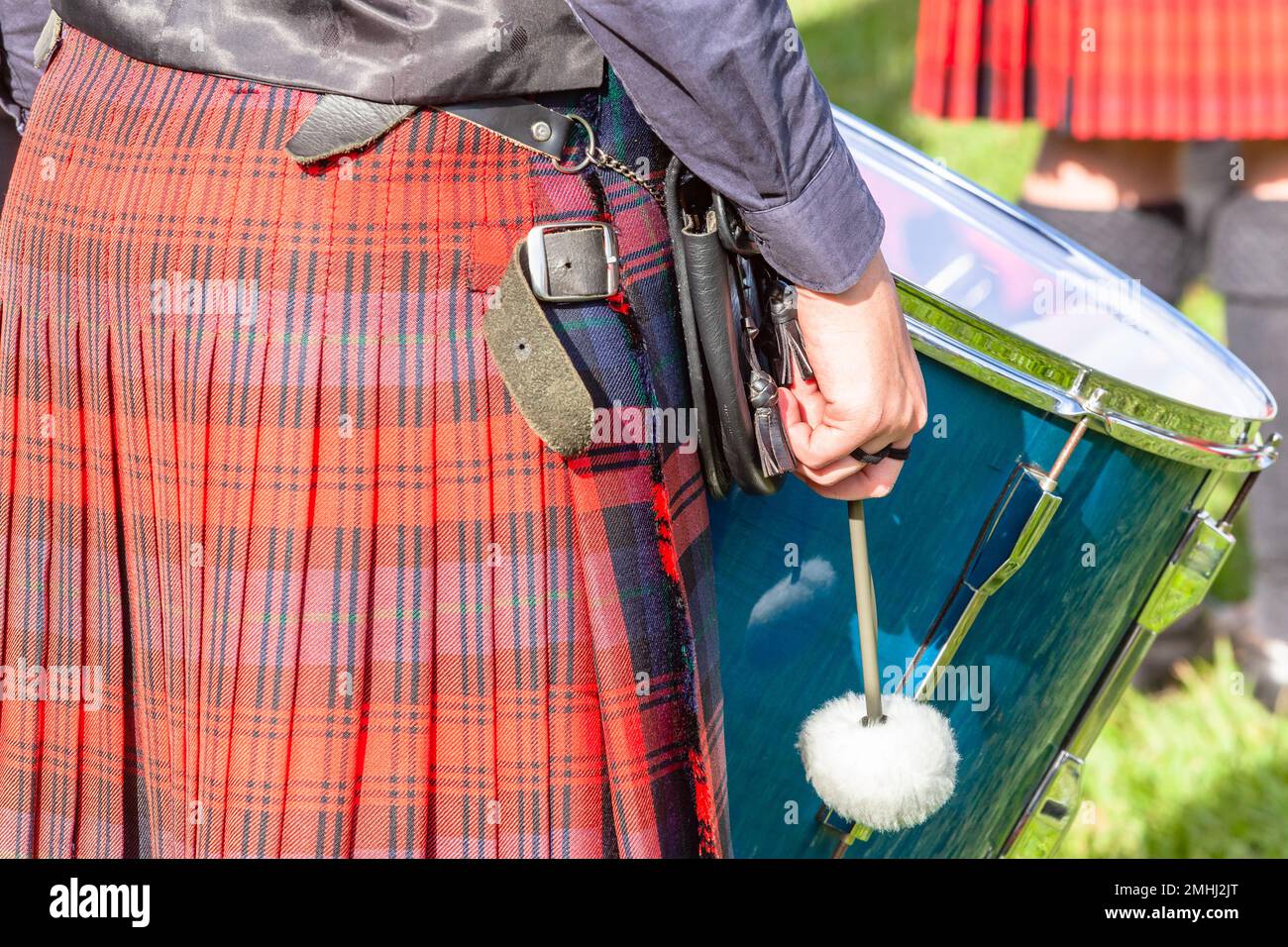 Schottischer Bandmusiker, Schlagzeuger aus nächster Nähe, Kilt Stick marschiert bei Highland-Spielen, ein Foto von hinten, Outdoor-Veranstaltungsort, sommerlicher blauer Himmel Stockfoto
