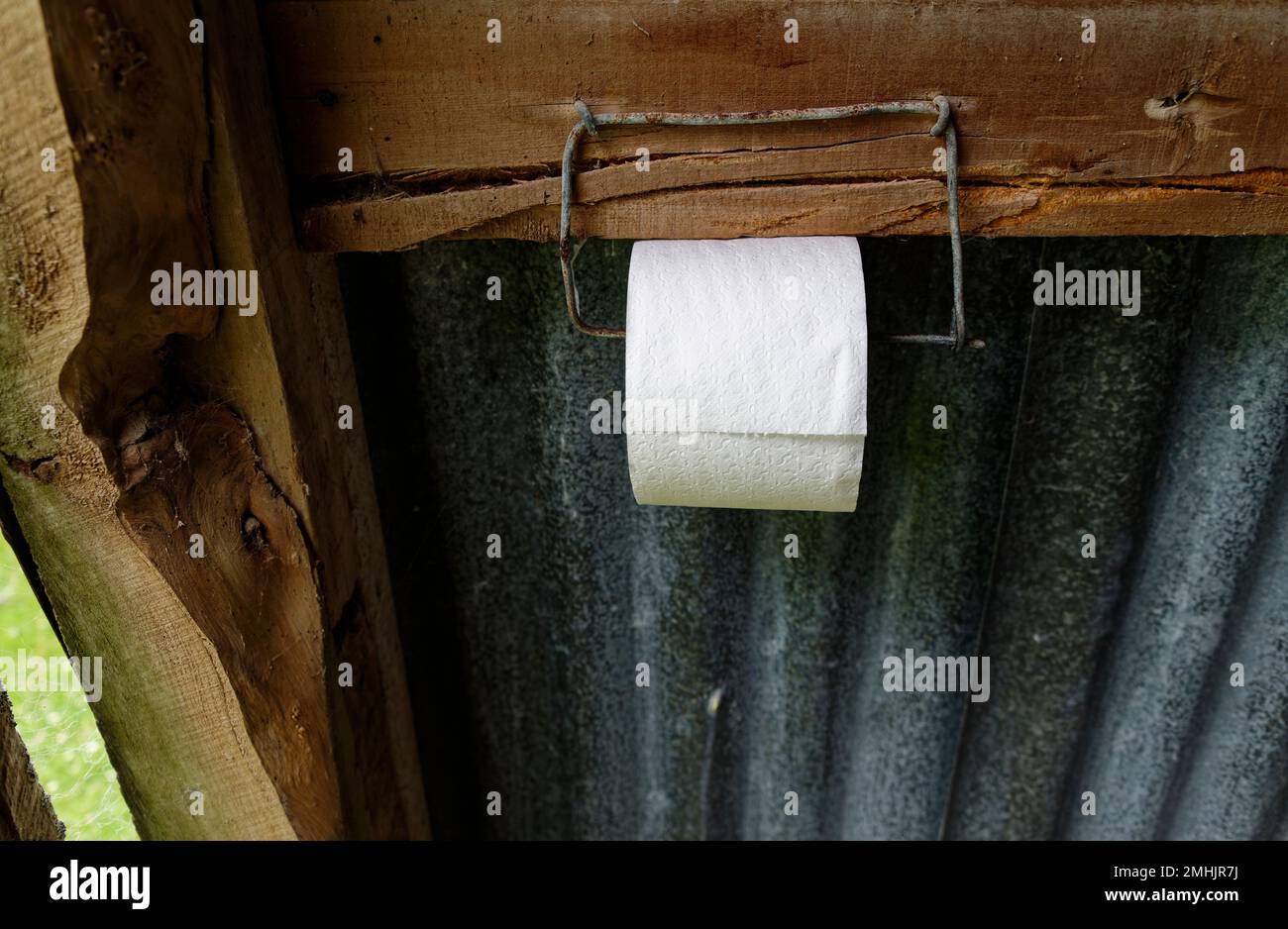 Ein Toilettenrollenhalter besteht aus Zaundraht Nummer 8. Da ist eine Rolle weißes Toilettenpapier drauf. Stockfoto