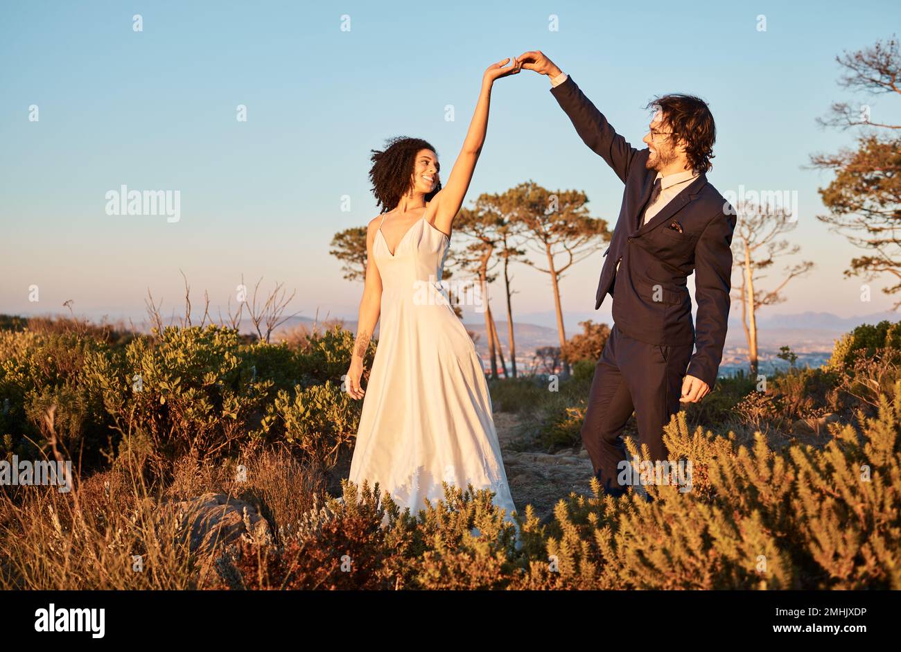 Liebe, Hochzeit und Händchenhalten zum Tanzen mit dem Paar im Naturpark für Feiern, Romantik und Glück. Sonnenuntergang, Unterstützung und Sommer mit Braut und Stockfoto