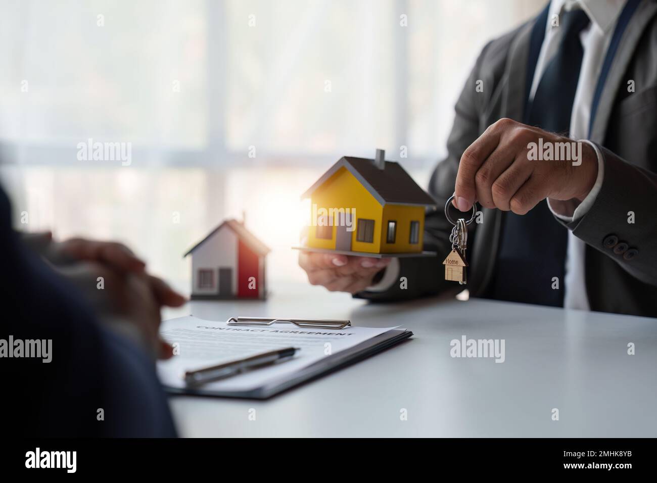 Nahaufnahme des Immobilienmaklers, um Häuser und Grundstücke zu kaufen, liefern Schlüssel und Häuser. Gespräch mit einem Immobilienmakler Stockfoto