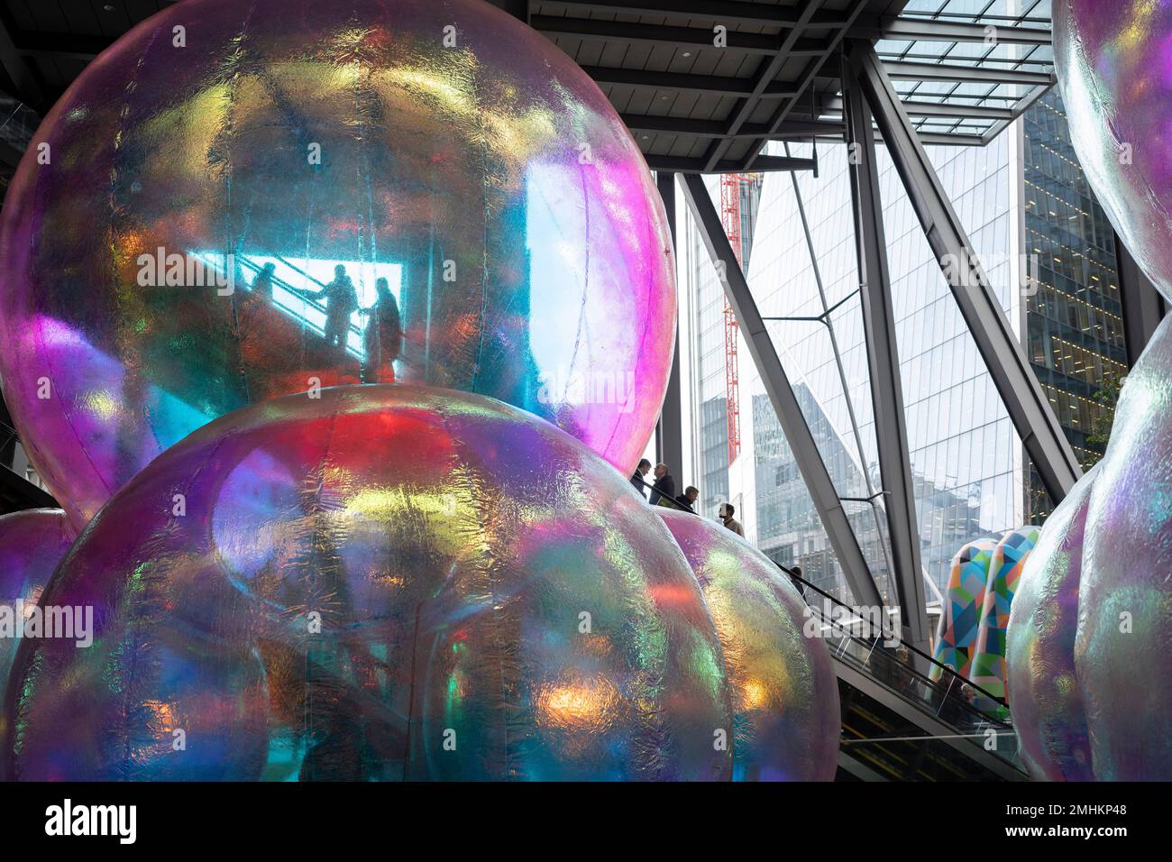 Büromitarbeiter fahren Rolltreppen über einem Kunstwerk mit dem Titel „Evanescent“, das im Januar und Februar darunter im Leadenhall Building in der City of London, dem Finanzviertel der Hauptstadt, am 26. Januar 2023 in London, England, ausgestellt wird. Evanescent ist ein kostenloser Besuch einer öffentlichen Anlage mit einer Ansammlung gigantischer Blasen, die zusammen auf mehr als sieben Meter Höhe steigen. Das Werk von Atelier Sisu wurde neben dem Westeingang des Leadenhall-Gebäudes, auch bekannt als „Cheesegrater“, platziert. Stockfoto