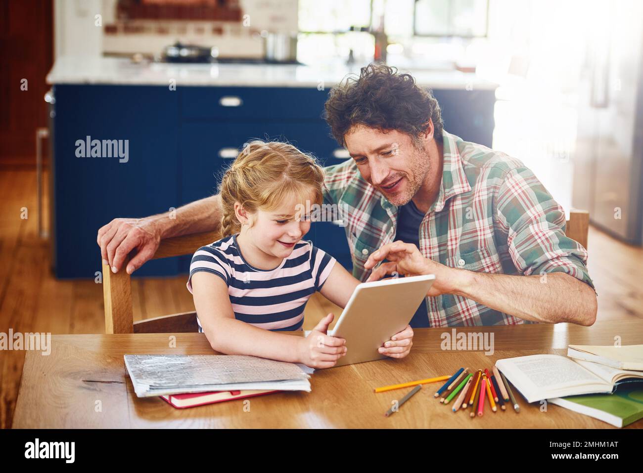 Und dann drückst du hier rüber... ein Vater, der seiner Tochter hilft, ihre Hausaufgaben auf einem digitalen Tablet zu erledigen. Stockfoto