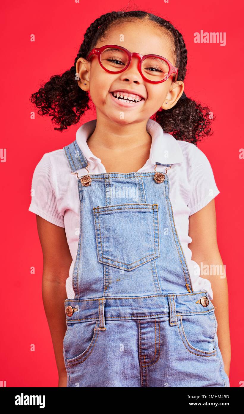 Glückliches Kind, Porträt- oder Modebrille auf rotem Hintergrund im Kinderstil, Augenpflege oder Wellness Gesundheit. Lächeln, Kind oder kleines Mädchen und Optometrie Stockfoto