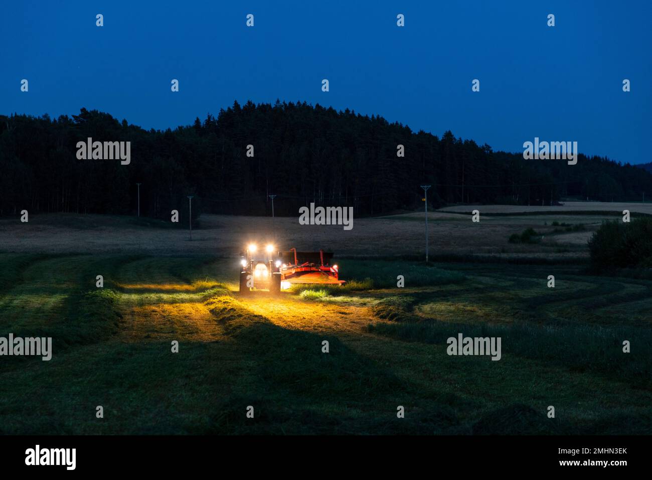 Landwirtschaftliche Maschine, die in der Dämmerung auf dem Hof arbeitet Stockfoto