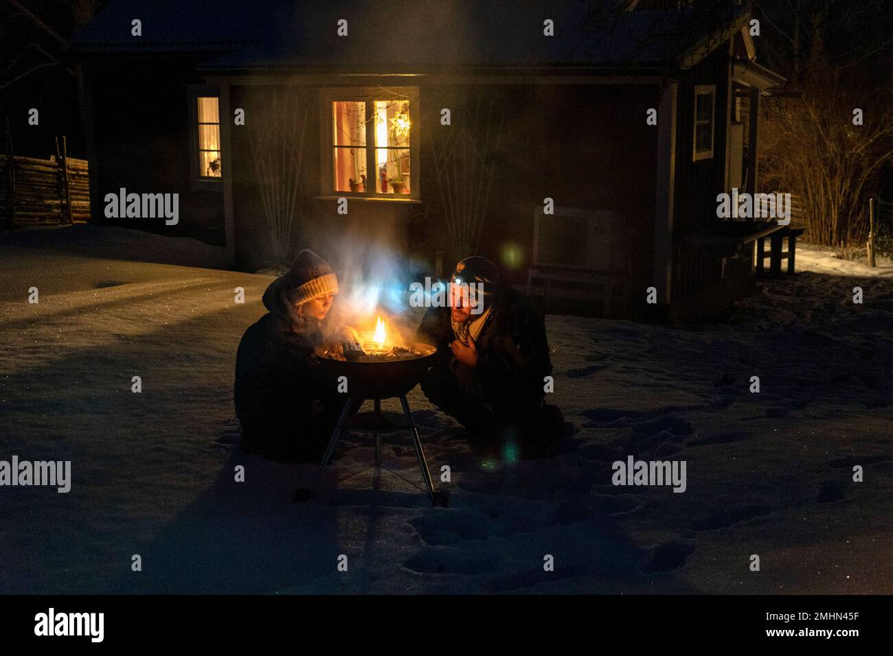 Mann und Frau beleuchten im Winter den Grill Stockfoto