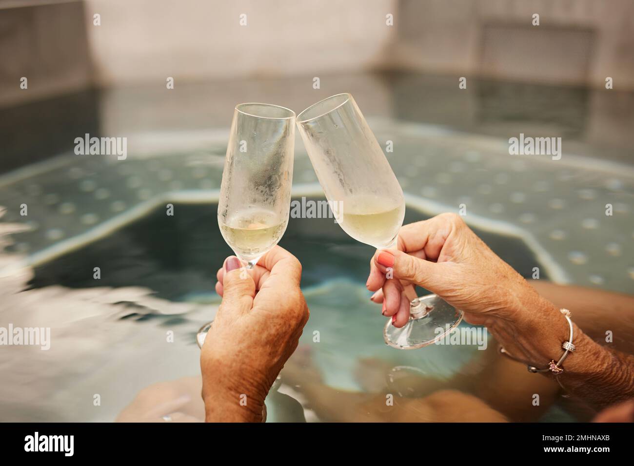 Hände halten Champagnerflöten im Whirlpool Stockfoto