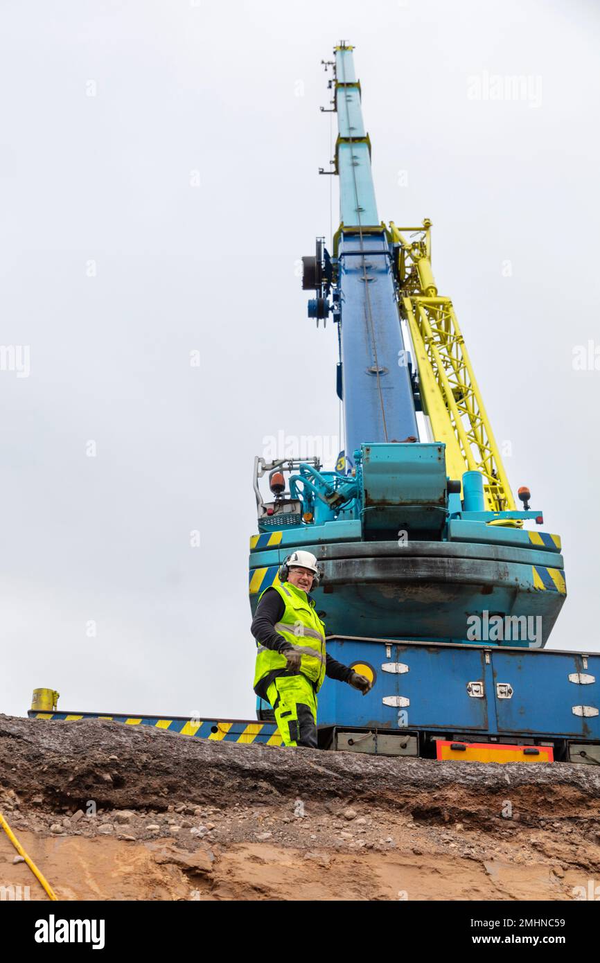 Mann, der neben einem Baufahrzeug steht Stockfoto