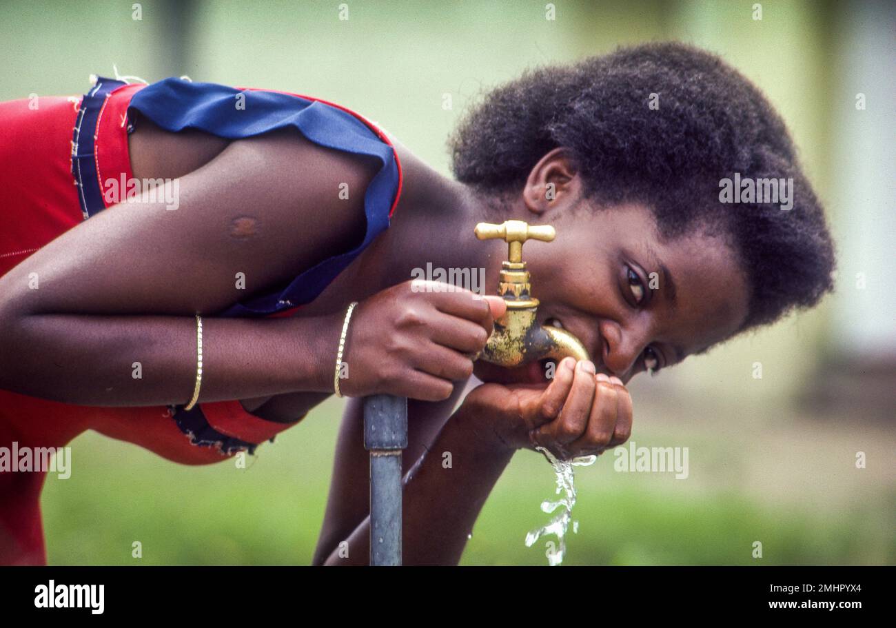 Sambia, Mongu. Frau, die aus dem Wasserhahn trinkt. Stockfoto