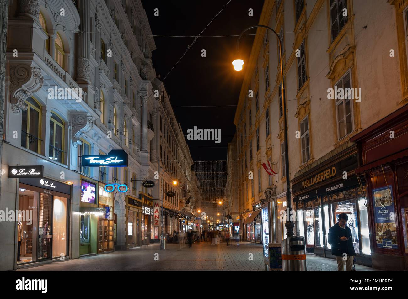 Die beleuchtete Altstadt von Wien auf dem Stephansplatz bei Nacht gefüllt mit Touristen in den Geschäften und Restaurants. Stockfoto