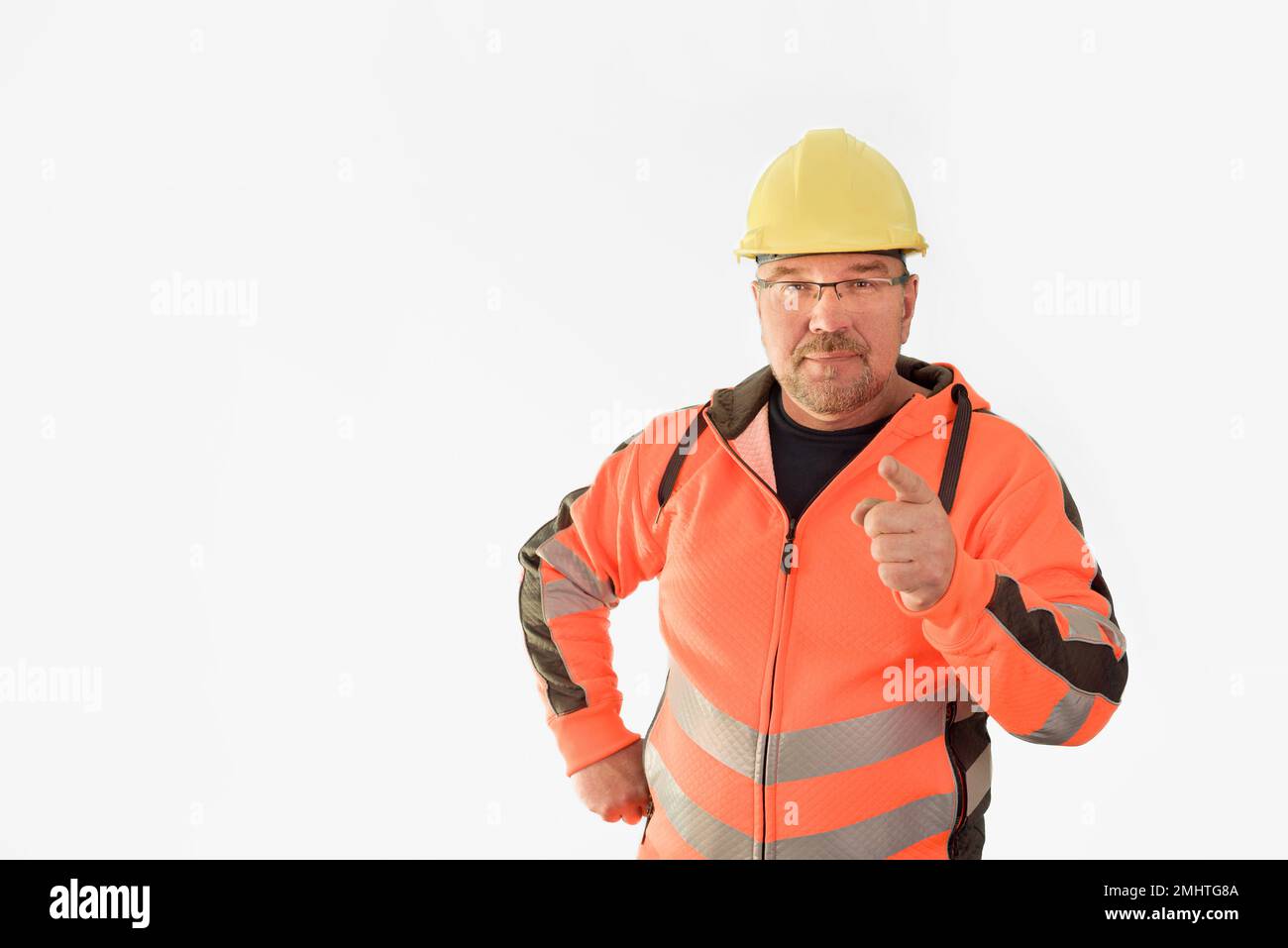 Porträt eines Baumechanikers, der die Kamera berät. Ein Baumeister mittleren Alters mit Bart in Schutzhelm und Uniform, isoliert auf weißem Backen Stockfoto