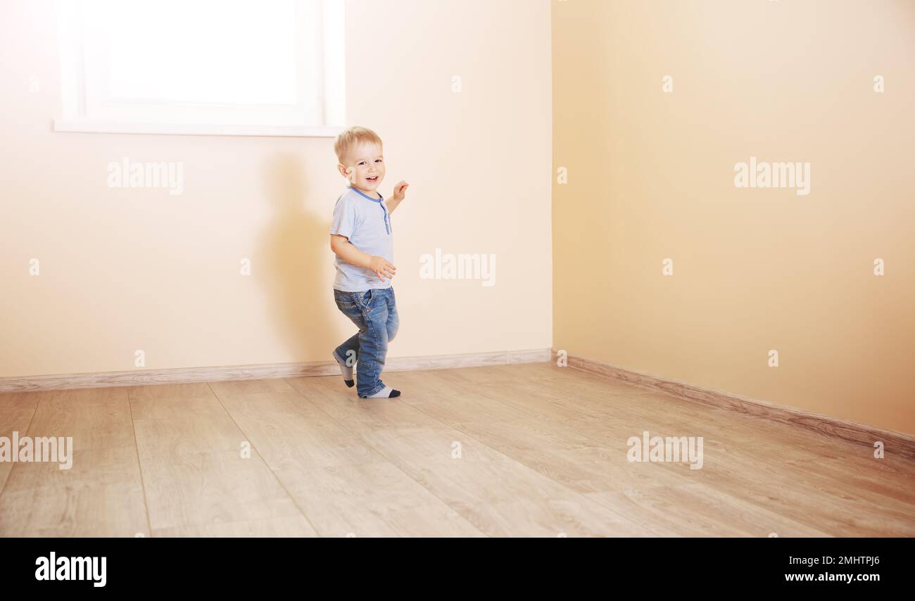 Ein lächelnder Junge, der in einem leeren Lichtzimmer rennt. Stockfoto