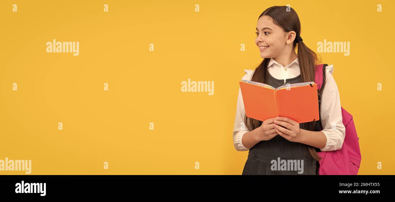 Lernen für das Leben. Glückliche Kinder lesen Bücher gelben Hintergrund. Porträt einer Schülerin, Studio-Banner-Header. Schulkindgesicht, Copyspace. Stockfoto