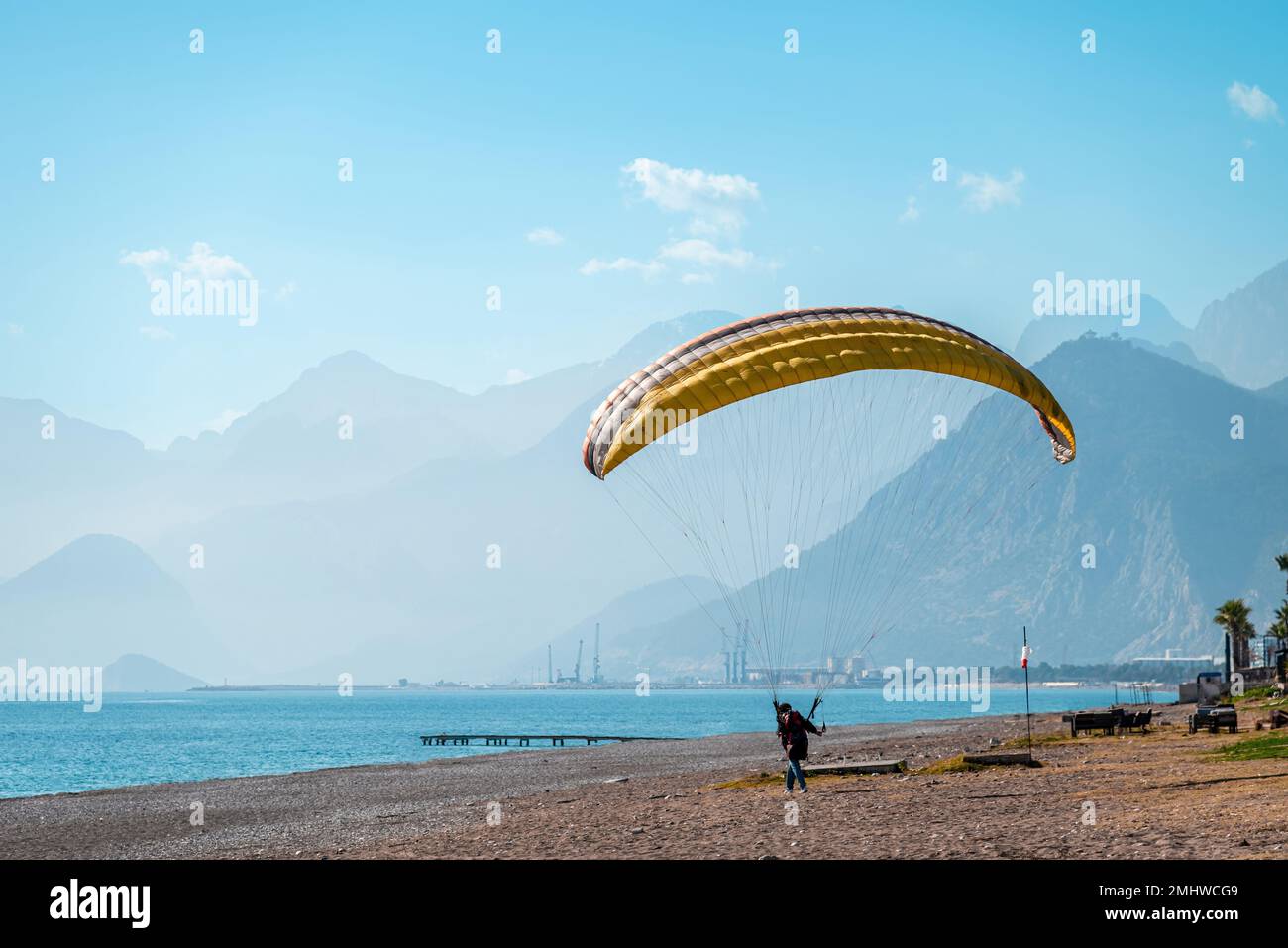 Ein Mann, der Gleitschirmfliegen an einem windigen Tag am Strand am Meer praktiziert Stockfoto