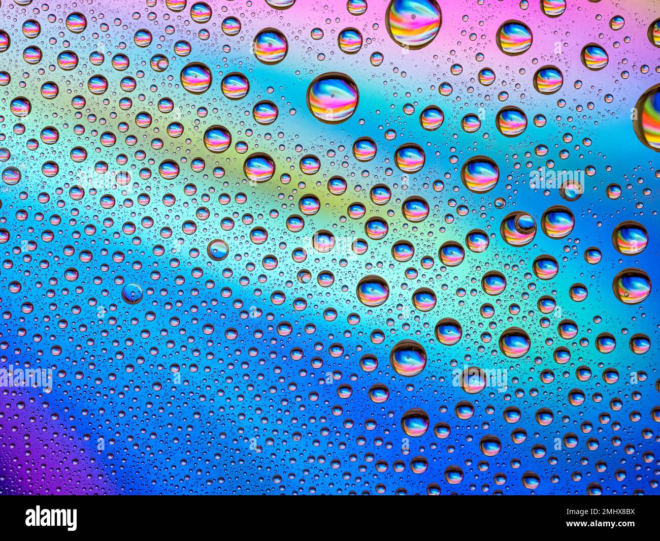 Das Wasser tropft über einem bunten abstrakten Hintergrund Stockfoto