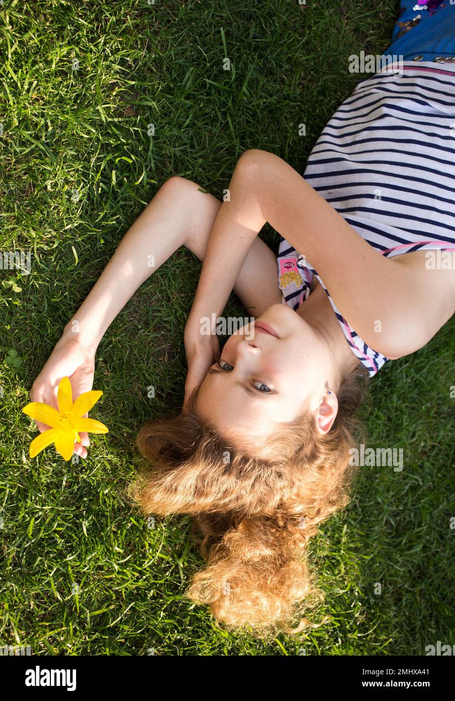 Hübsches Mädchen, 11-12 Jahre alt, liegt auf dem Rasen an einem sonnigen Sommertag, sonnt sich. Erholung mit Vergnügen in der Natur. Tag der Erde. Unachtsamkeit, Harmo Stockfoto