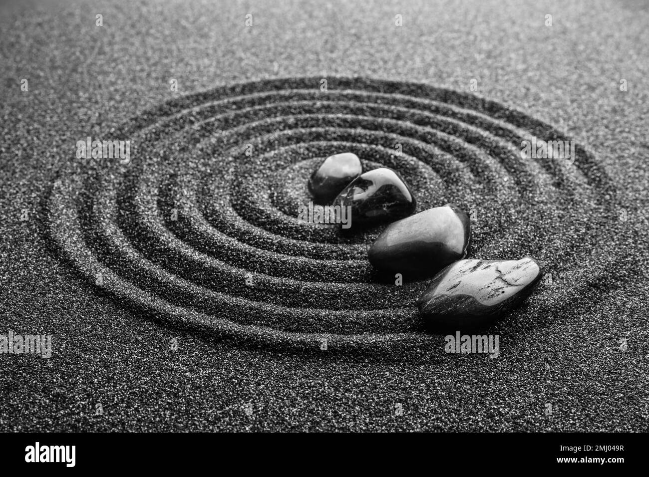 Schwarzer Sand mit Steinen und wunderschönem Muster. Zen-Konzept Stockfoto