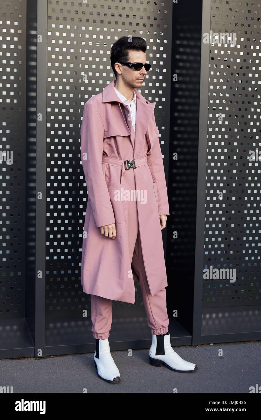 MAILAND, ITALIEN - 13. JANUAR 2023: Mann mit pinkfarbenem Trenchcoat, Hose und weißen Stiefeln vor der Gucci-Modenschau, Mailand Fashion Week Street Style Stockfoto