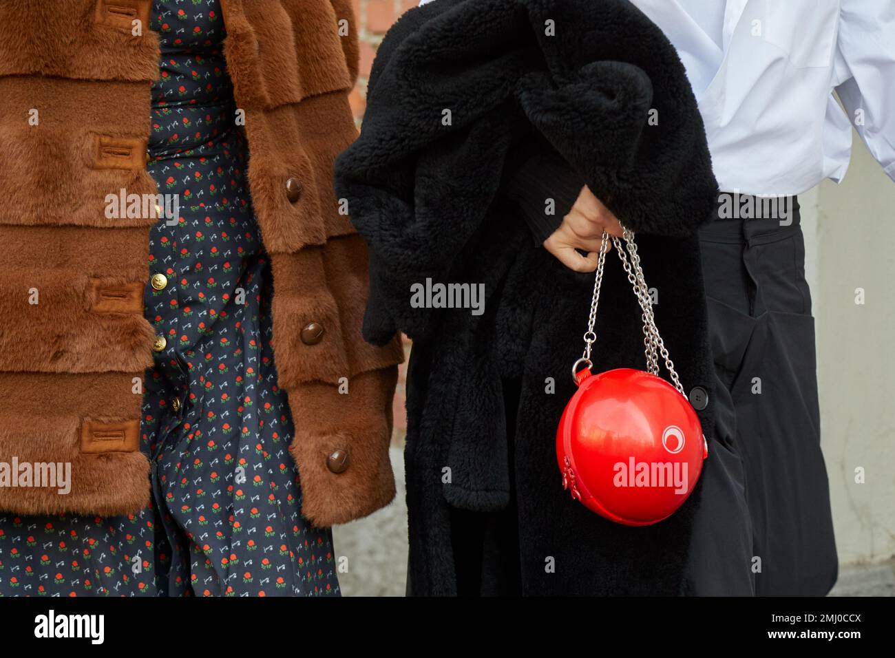MAILAND, ITALIEN - 14. JANUAR 2023: Frau mit braunem Pelzmantel und roter kugelförmiger Tasche vor der Fendi-Modenschau, Mailand Fashion Week Street Style Stockfoto