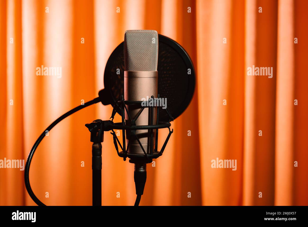 Mikrofonkondensor mit Schalldämmung in Recording Studio Shadow Silhouette in orangefarbenem Neonlicht, Nahaufnahme Stockfoto