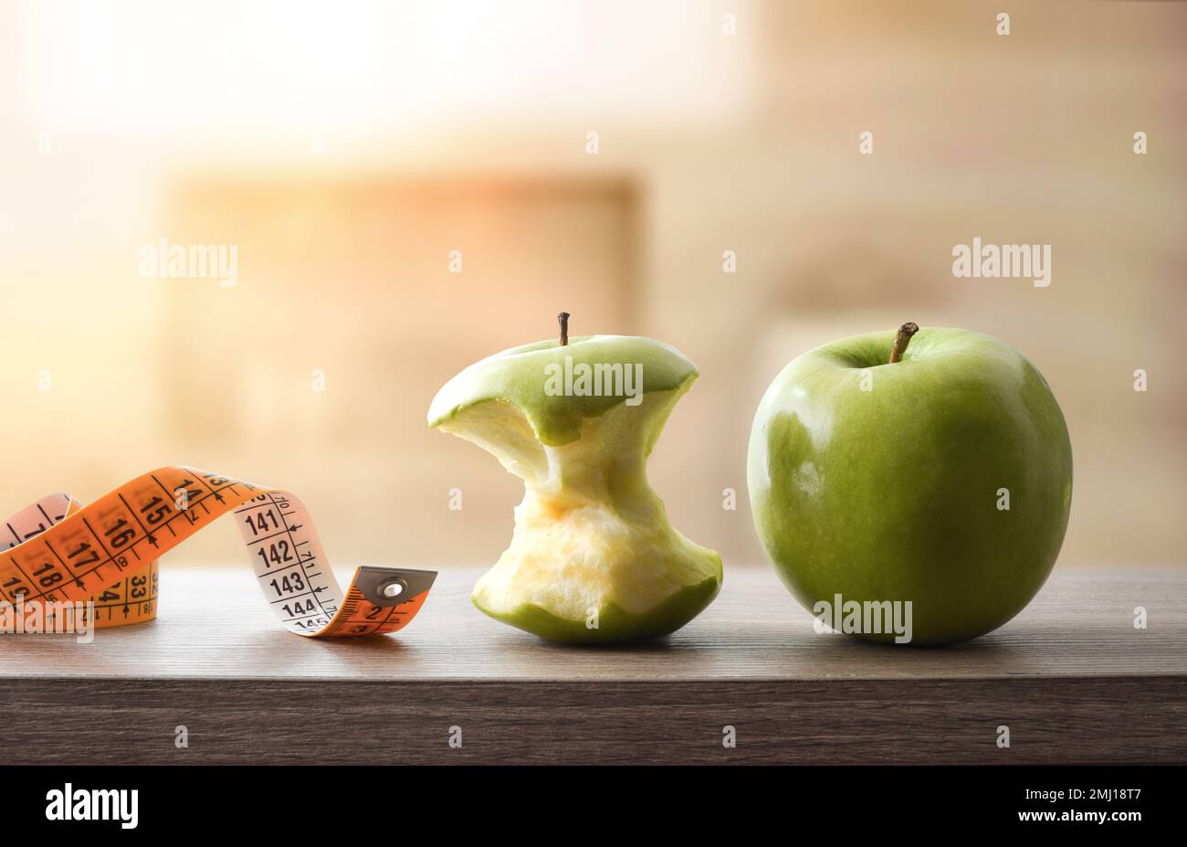 Gesundes Lifestyle-Konzept mit Apfel- und Bandmaß auf Holztisch und Naturhintergrund. Vorderansicht. Stockfoto
