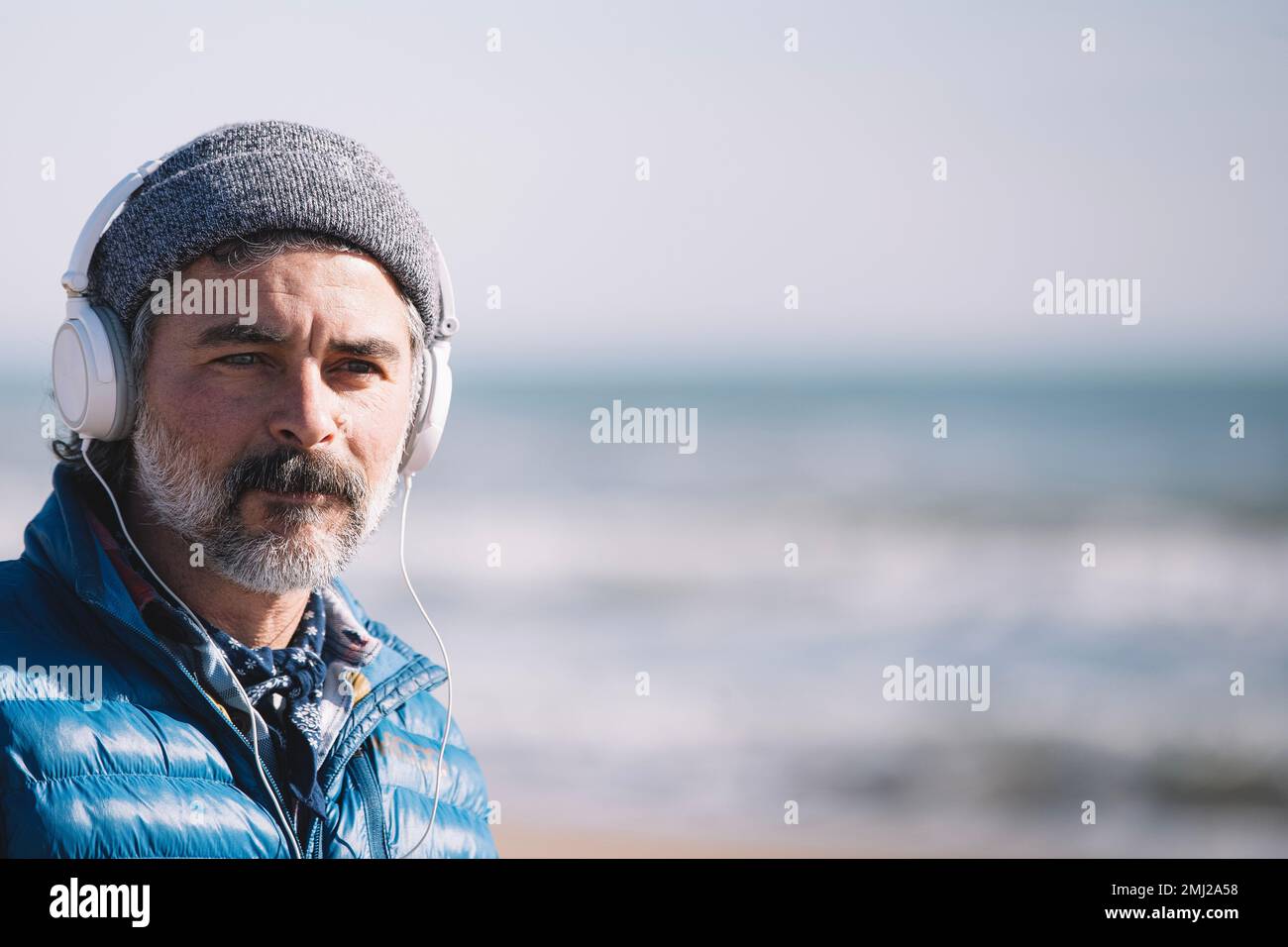Erwachsener Mann mit Kopfhörern am Strand. Speicherplatz kopieren Stockfoto