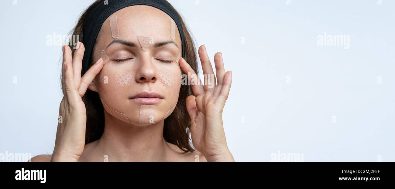 Schönheitskonzept Gesichtspflege Frau, die kinesiologische Gesichtsbänder auf ihr Gesicht aufklebt, Anti-Falten-Therapie. Stockfoto