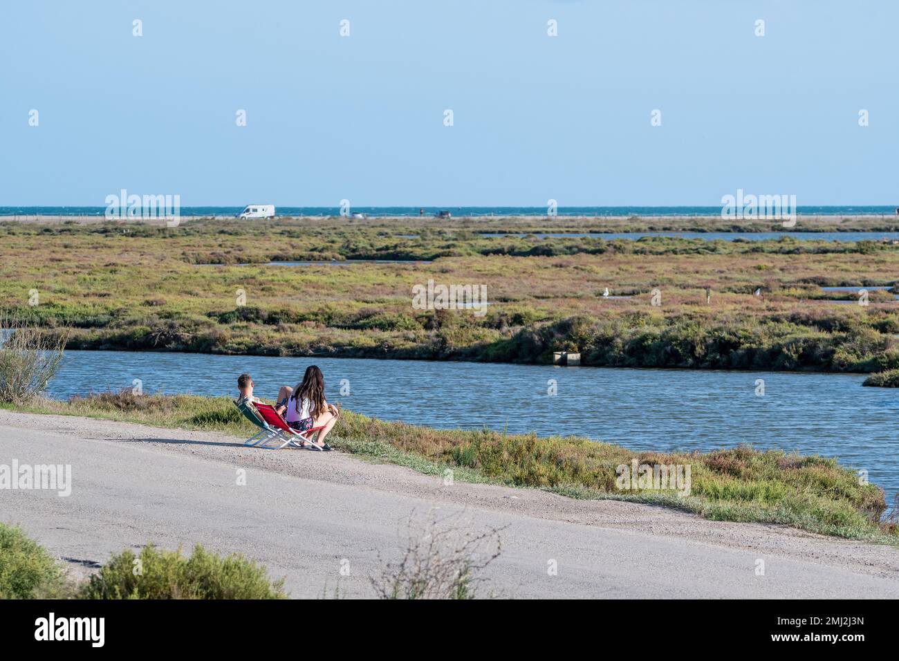 Ein Paar, das auf Campingstühlen sitzt und die Lagunen an der Straße beobachtet. Ebro Delta, Katalonien, Spanien Stockfoto