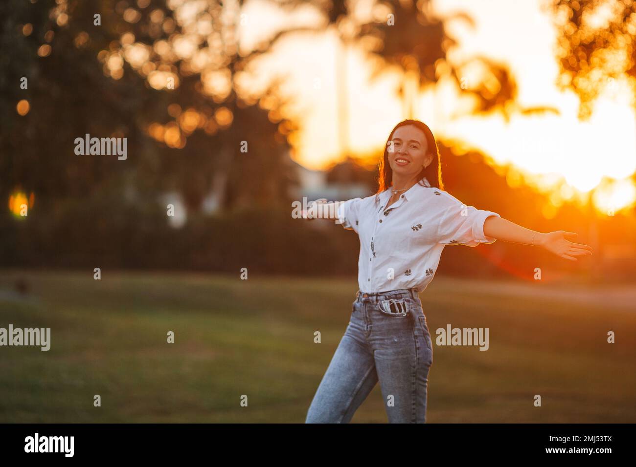 Porträt einer glücklichen jungen Frau im Park bei Sonnenuntergang Stockfoto