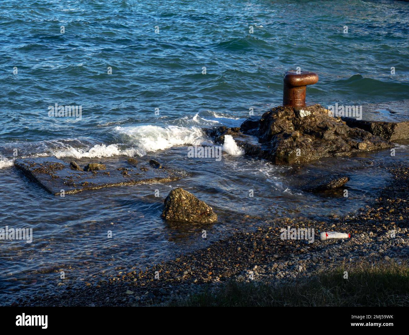 Der alte rostige Poller am Meer. Batumi. Das Meer überwältigt den Pier. Alte Betonplatten am Ufer. Befestigte Küste. Schwarzes Meer. Stockfoto