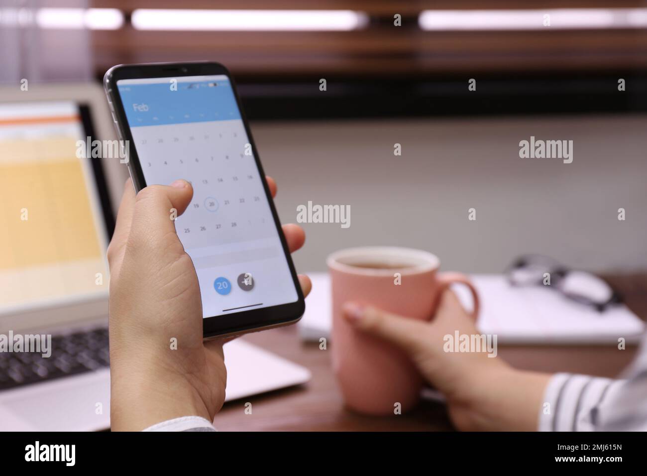 Frau mit Smartphone und Kalender-App am Tisch, Nahaufnahme Stockfoto