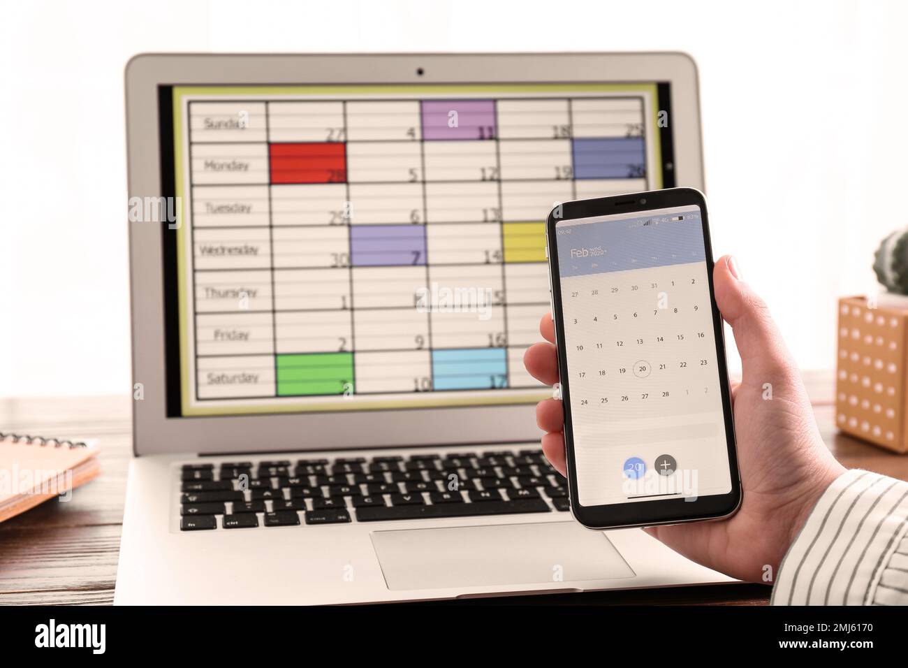 Frau mit Smartphone und Kalender-App am Tisch, Nahaufnahme Stockfoto