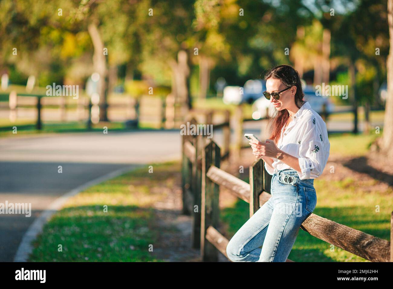 Junge Frau, die im Park ein Handy benutzt Stockfoto
