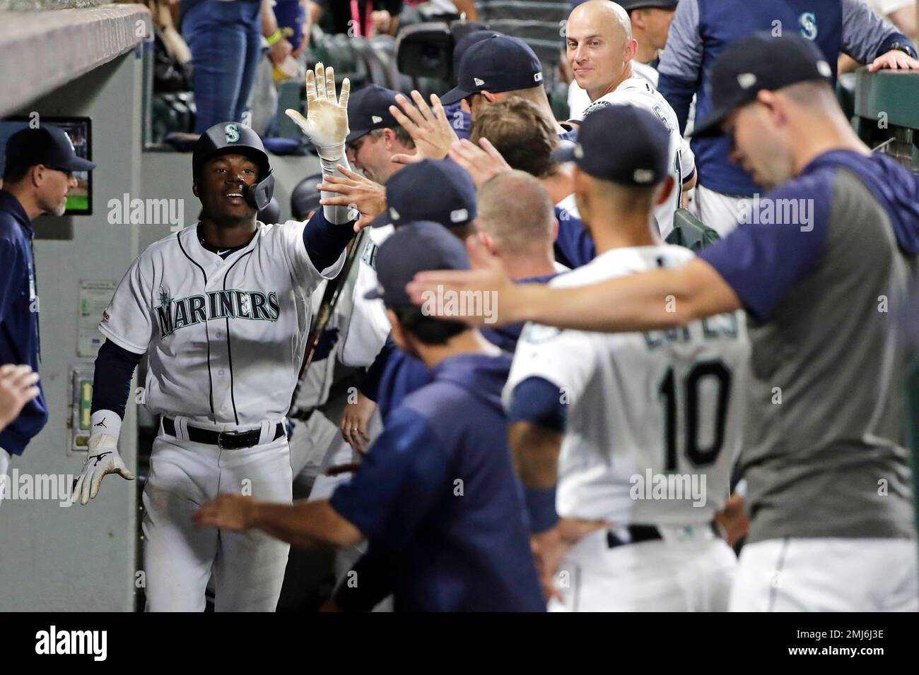 Teammates line up to greet Seattle Mariners' Kyle Lewis, left, in the