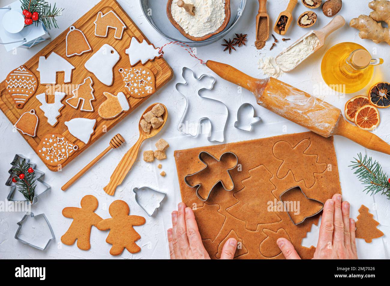 Weihnachtliches Lebkuchen in unterschiedlicher Form mit Zutaten für Lebkuchen und den Händen einer Bäckerin, Draufsicht, flach liegend Stockfoto