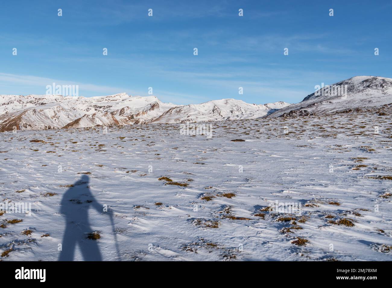 Schatten eines Bergsteigers im Schnee der Sierra Nevada, mit den Mulhacen- und Veleta-Gipfeln im Hintergrund. Granada. Stockfoto