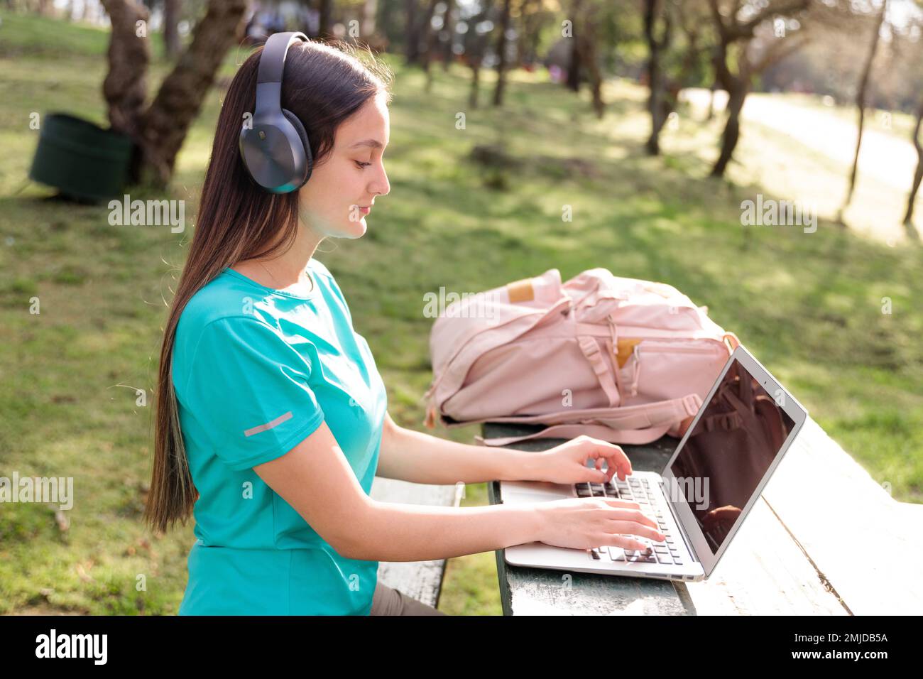 Studentin, die draußen im Park sitzt und einen Laptop benutzt Stockfoto