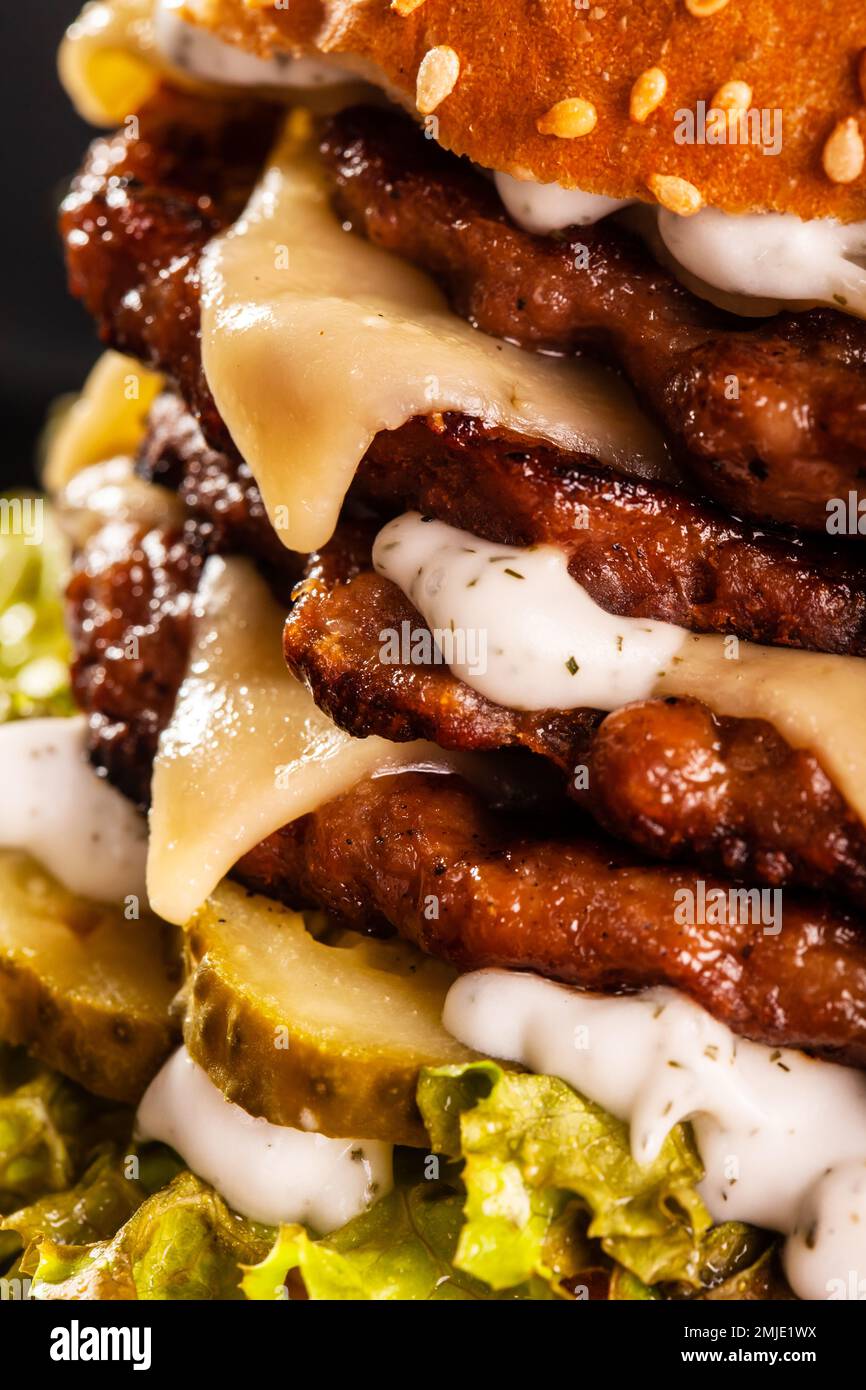 Abstraktes Junk Food. Vierfacher Burger mit Käsegurke und Salat. Hintergrundstruktur für Fast Food. Stockfoto