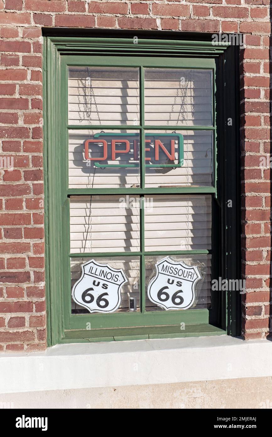 Am Fenster des Mother Road Museum in Barstow, Kalifornien, befinden sich ein offenes Neonschild und zwei US 66-Schilder, eines für Illinois und eines für Missouri. Stockfoto