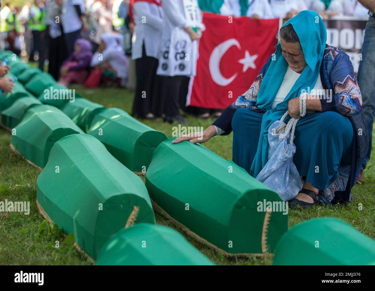 A woman mourns next to the coffins in Potocari near Srebrenica, Bosnia, Thursday, July 11, 2019. The remains of the 33 victims of Srebrenica massacre will be buried 24 years after Serb troops overran the eastern Bosnian Muslim enclave of Srebrenica and executed some 8,000 Muslim men and boys, which international courts have labeled as an act of genocide. (AP Photo/Darko Bandic) Stockfoto