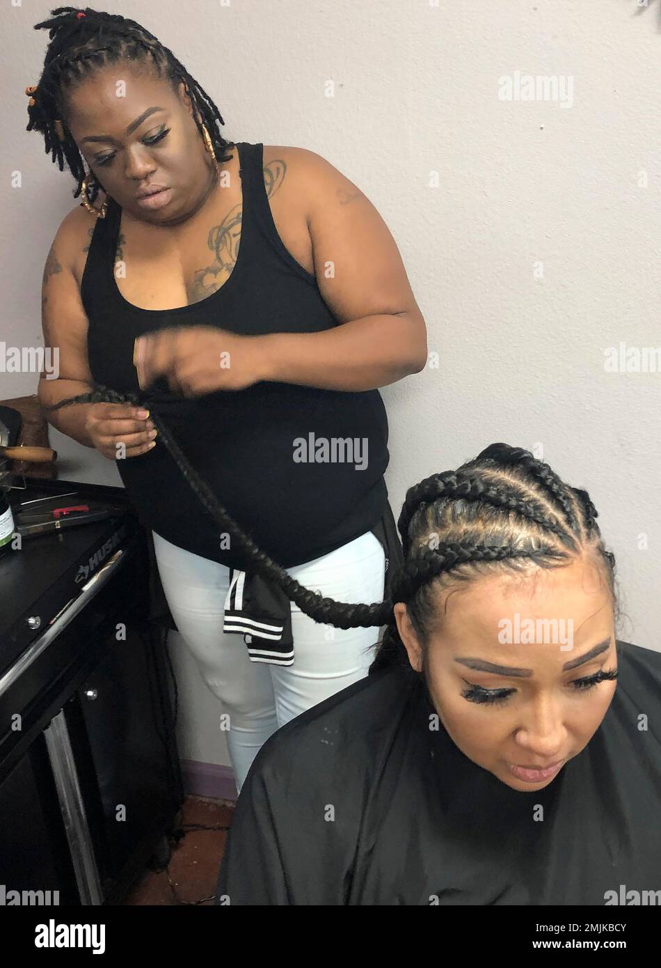 Elicia Drayton, left, braids the hair of Shereen Africa at Exquisite U hair salon in Sacramento, Calif., Wednesday, July 3, 2019. California is the first state to ban job and school discrimination against people for wearing natural hair styles such as braids. Gov. Gavin Newsom, a Democrat, signed the legislation Wednesday. (AP photo/Kathleen Ronayne) Stockfoto