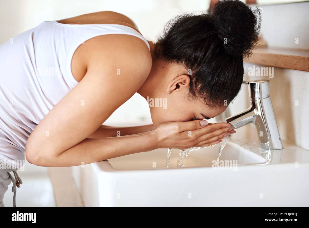 Aufwachen mit einem erfrischenden Spritzer. Eine junge Frau, die sich im Bad das Gesicht wäscht. Stockfoto