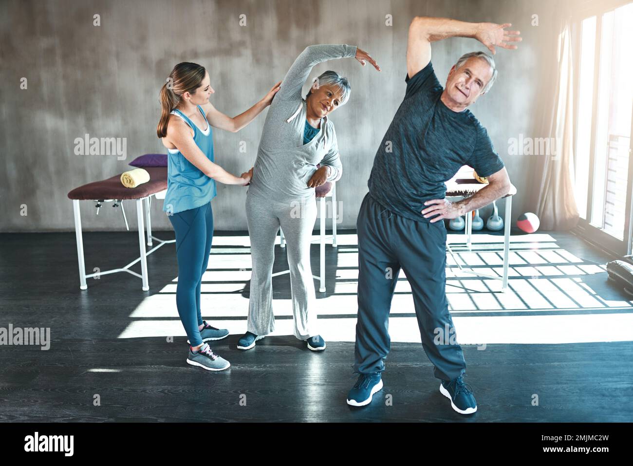 Egal, wie alt du bist, Bewegung nützt uns allen. Ein älterer Mann und eine ältere Frau, die mit Hilfe eines Lehrers trainieren. Stockfoto