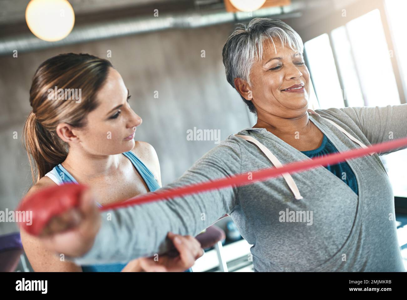 Mit Sport werden die goldenen Jahre immer besser. Eine Seniorin, die mit Hilfe eines Physiotherapeuten Resistenzbänder benutzt. Stockfoto