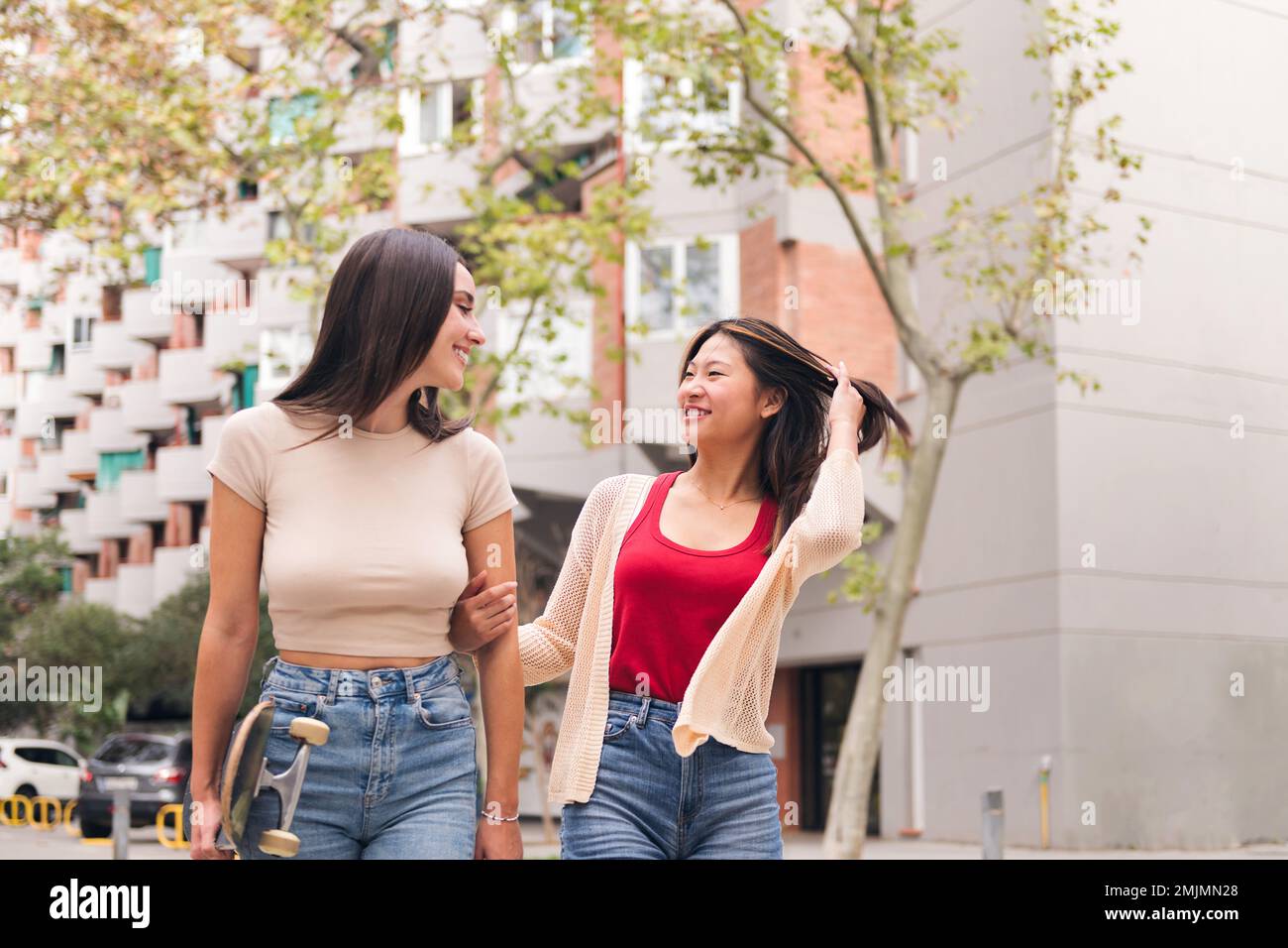Frauen, die Arm in Arm durch die Stadt schlendern Stockfoto