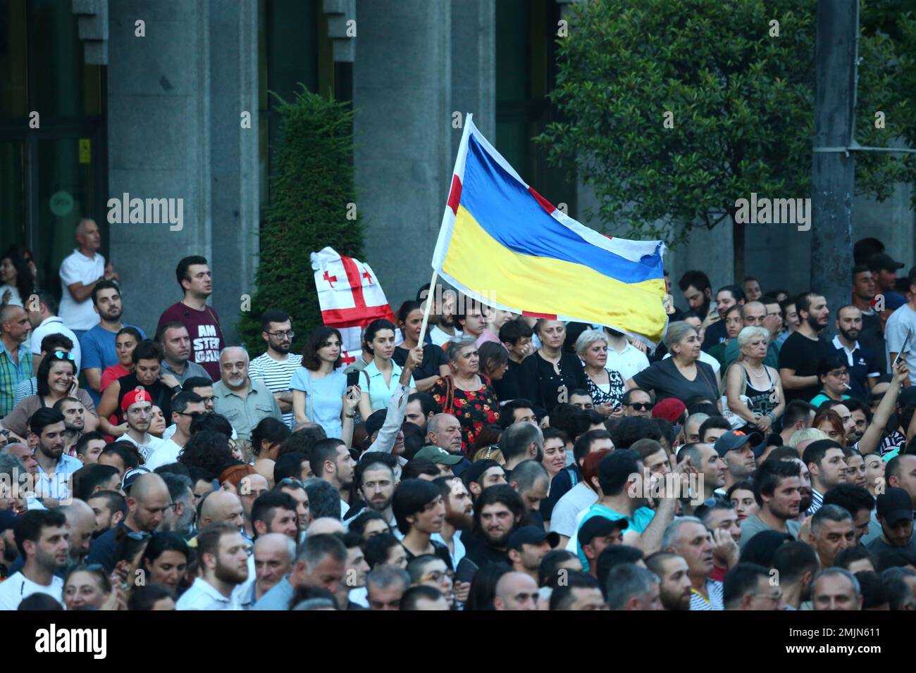 Opposition demonstrators waves the Georgian and Ukrainian national flag as they gather in front of the Georgian Parliament building in Tbilisi, Georgia, Friday, June 21, 2019. Several thousand protesters returned to the parliament building Friday, demanding that the interior minister resign over the heavy-handed police action. Many in the crowd wore eyepatches in a sign of solidarity with those who lost their eyes during police crackdown. (AP Photo/Zurab Tsertsvadze) Stockfoto