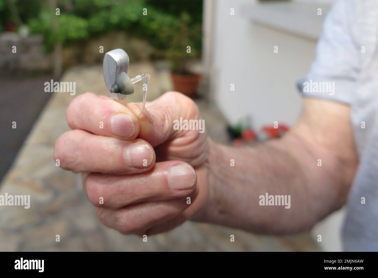 Nahaufnahme Hand Mann mit Hörgerät auf unscharfem Hintergrund Stockfoto