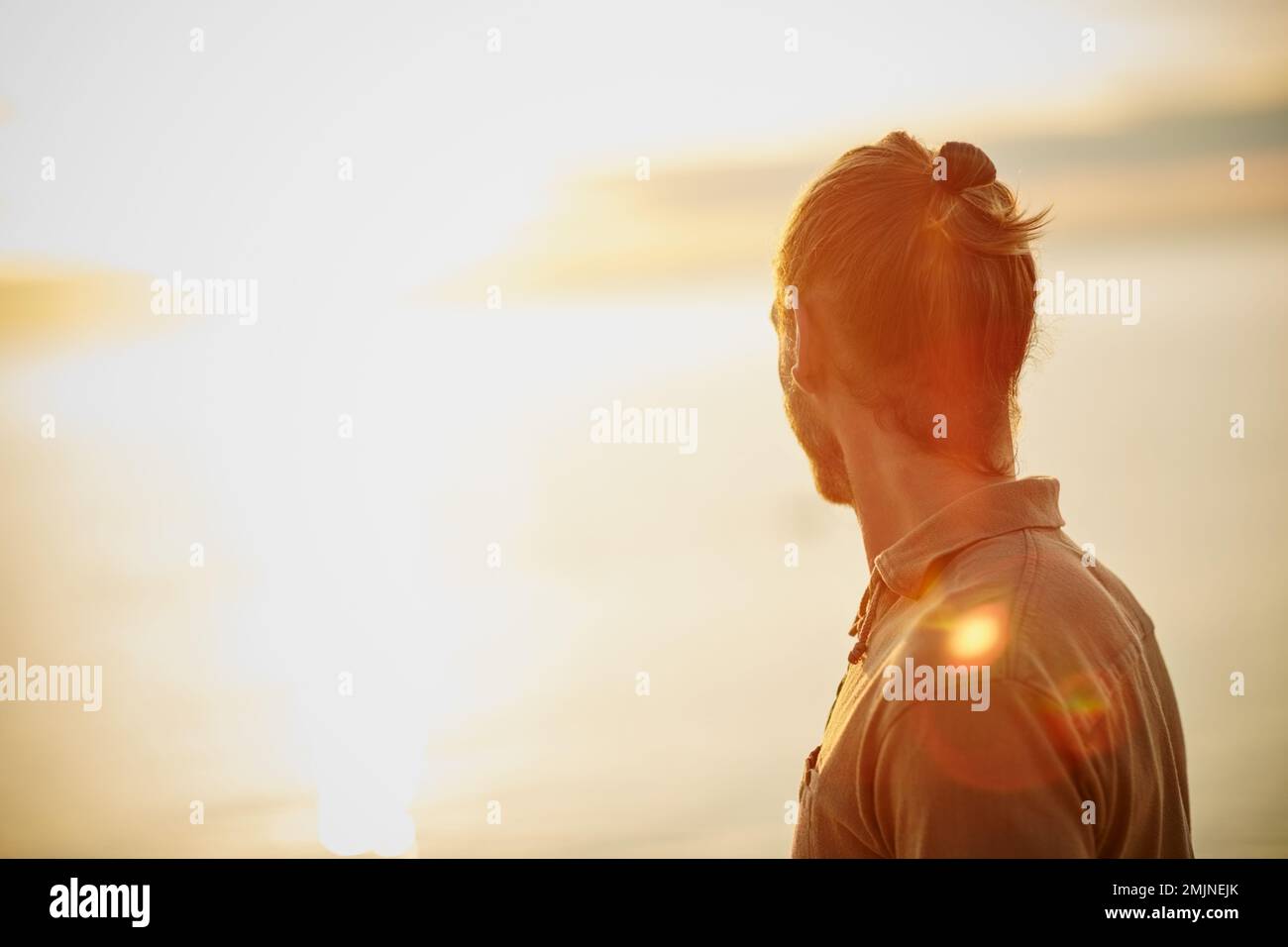 Sei still und wertschätze das Leben. Ein Mann, der den Sonnenuntergang am Strand beobachtet. Stockfoto