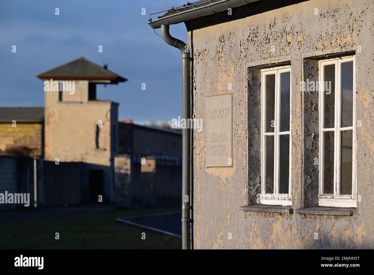 Oranienburg, Deutschland. 27. Januar 2023. Die Kaserne „Pathologie“ und ein ehemaliger Wachturm stehen auf dem Gelände des Sachsenhausen-Gedenkmals und -Museums. Während einer gemeinsamen Veranstaltung des Brandenburger Landesparlaments und der Gedenkstätte wurde zum ersten Mal, anstatt einen Kranz zu legen, eine Tonband-Kunstaktion mit der Frage durchgeführt: "Warum erinnern Sie sich heute? Kredit: Soeren Stache/dpa/Alamy Live News Stockfoto