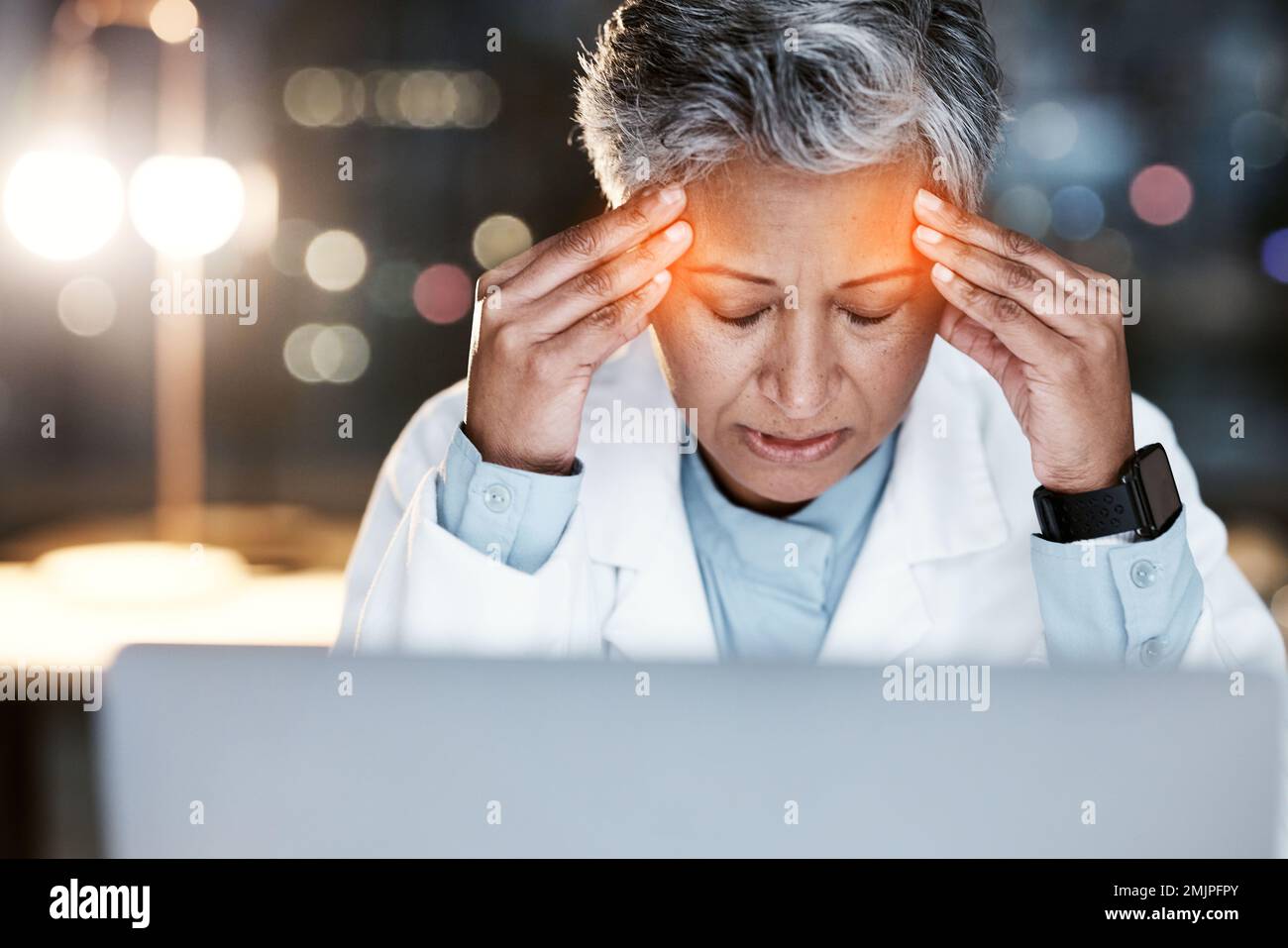 Nacht, Stress und Kopfschmerzen mit dem Arzt am Laptop zur medizinischen, Stress- und Terminübersicht. Burnout, Rechenschaftspflicht und psychische Gesundheit bei Seniorin Stockfoto