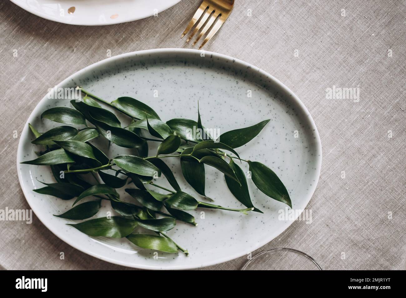 Rustikaler Hochzeitstisch mit alten Tellern, grüner und weißer Eukalyptusgirlande, goldenen Utensilien. Boho-Stil. Tabellenset für ein Ereignis, eine Partei, ein Datum oder Stockfoto